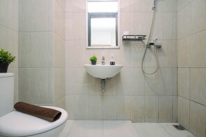 Ein Badezimmer mit Toilette, Waschbecken, Dusche und einem kleinen Fenster.