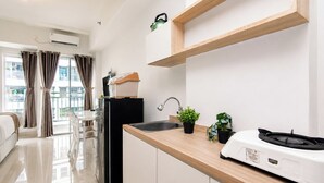 Una cocina moderna con un lavamanos, encimera y hervidor. Hay un comedor con mesa y sillas, y vistas a edificios.