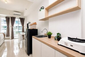 Eine moderne Küche mit Spüle, Arbeitsplatte und Wasserkocher. Es gibt einen Essbereich mit Tisch und Stühlen sowie einen Blick auf Gebäude im Freien.