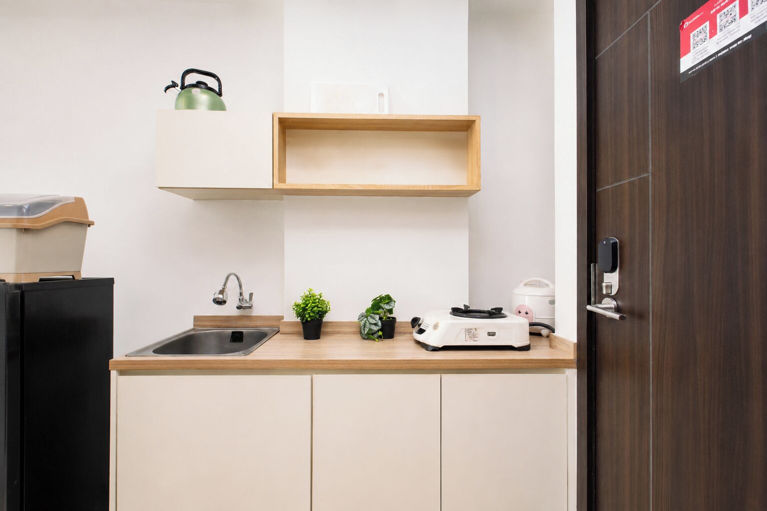 A kitchen with a sink, a kettle, a toaster, and a small potted plant.