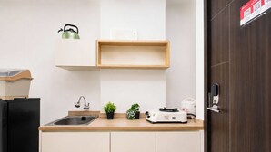 Una cocina con un lavamanos, un hervidor, una tostadora y una pequeña planta en maceta.