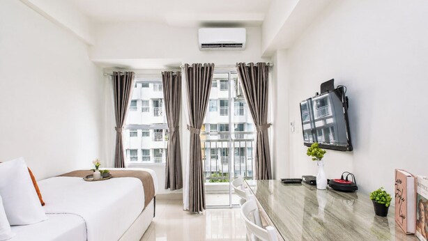 Habitación de hotel con cama, una mesa de comedor, televisión y balcón con cortinas.