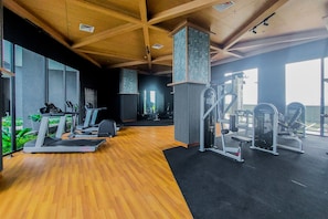 Ein Fitnessstudio mit Laufbändern, Kraftgeräten und Holzboden.