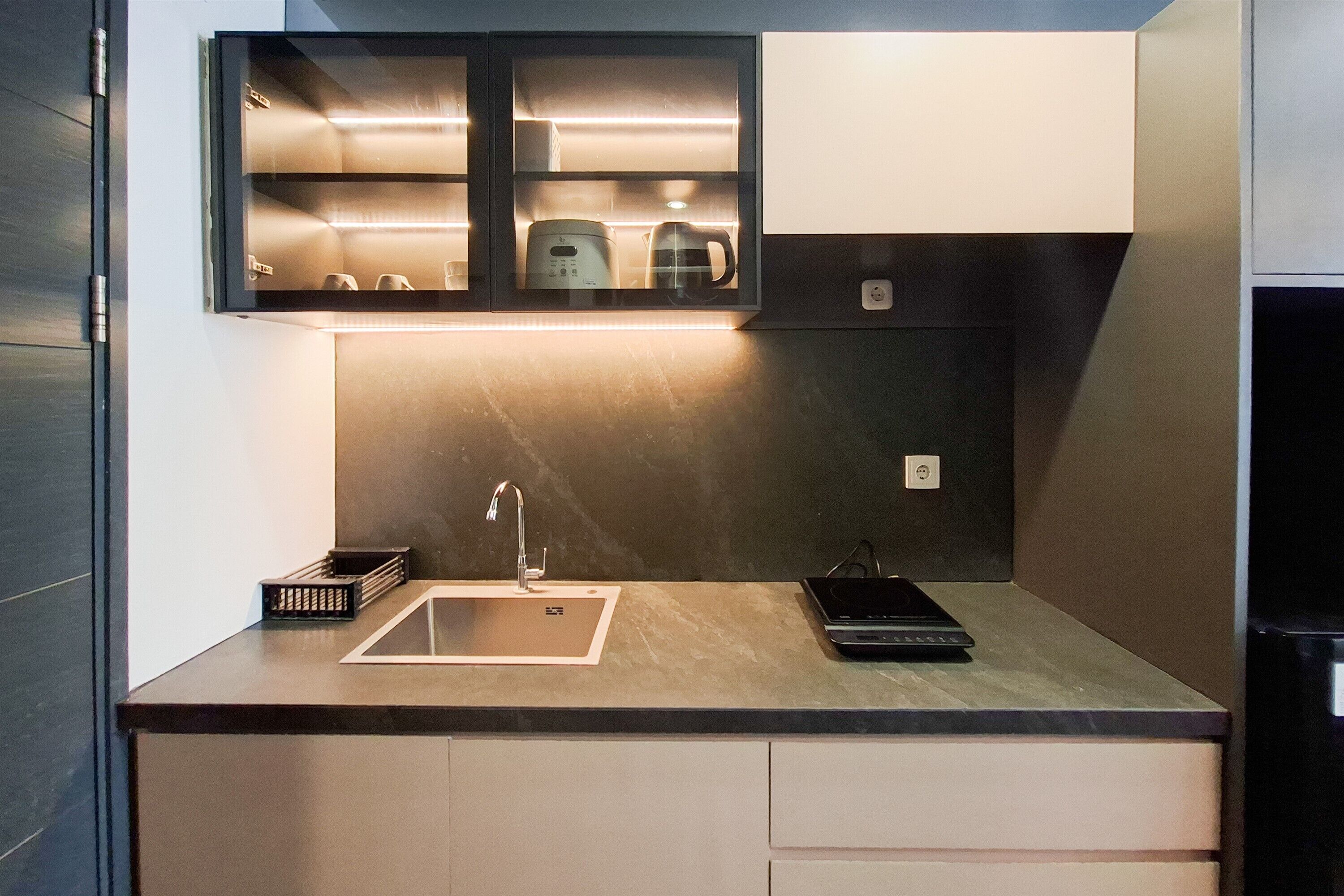 Una cocina moderna con microondas integrado, cafetera y lavabo.