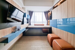 Ein modernes Zimmer mit einem Bett, einem Fernseher und einem Fenster mit Vorhängen.