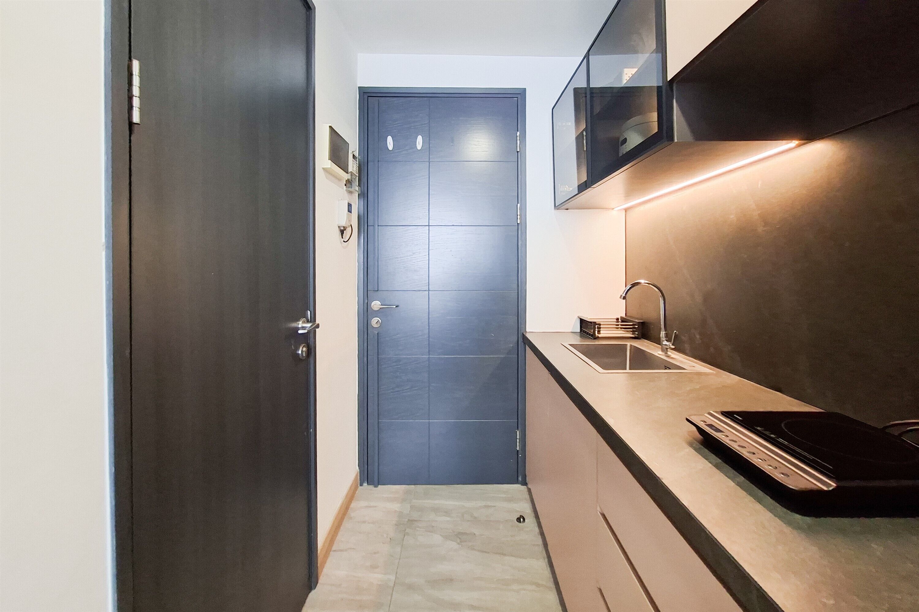 A modern kitchen with a dark door, a sink, and a countertop.