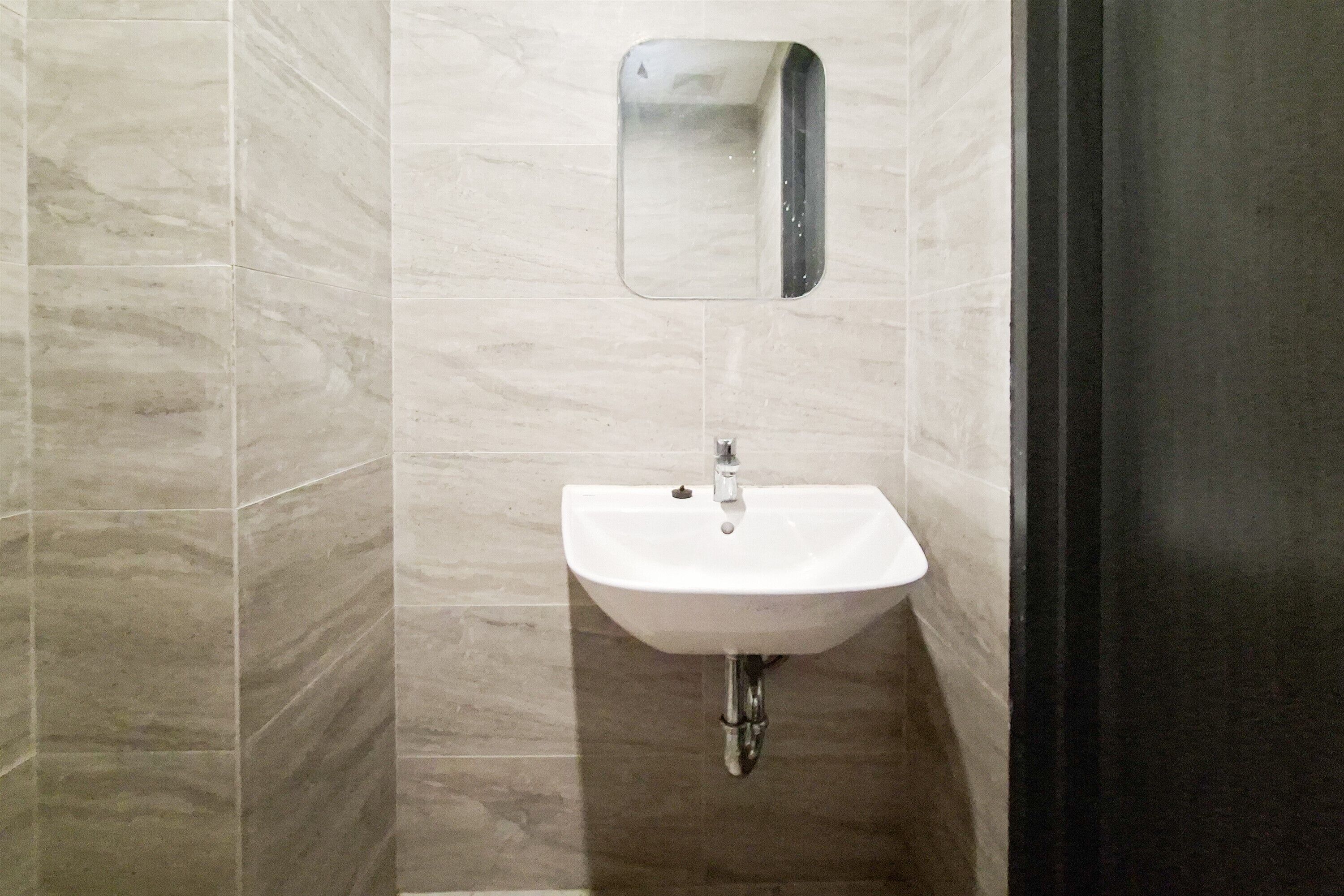 Une salle de bain avec un lavabo blanc, un miroir et des murs carrelés.