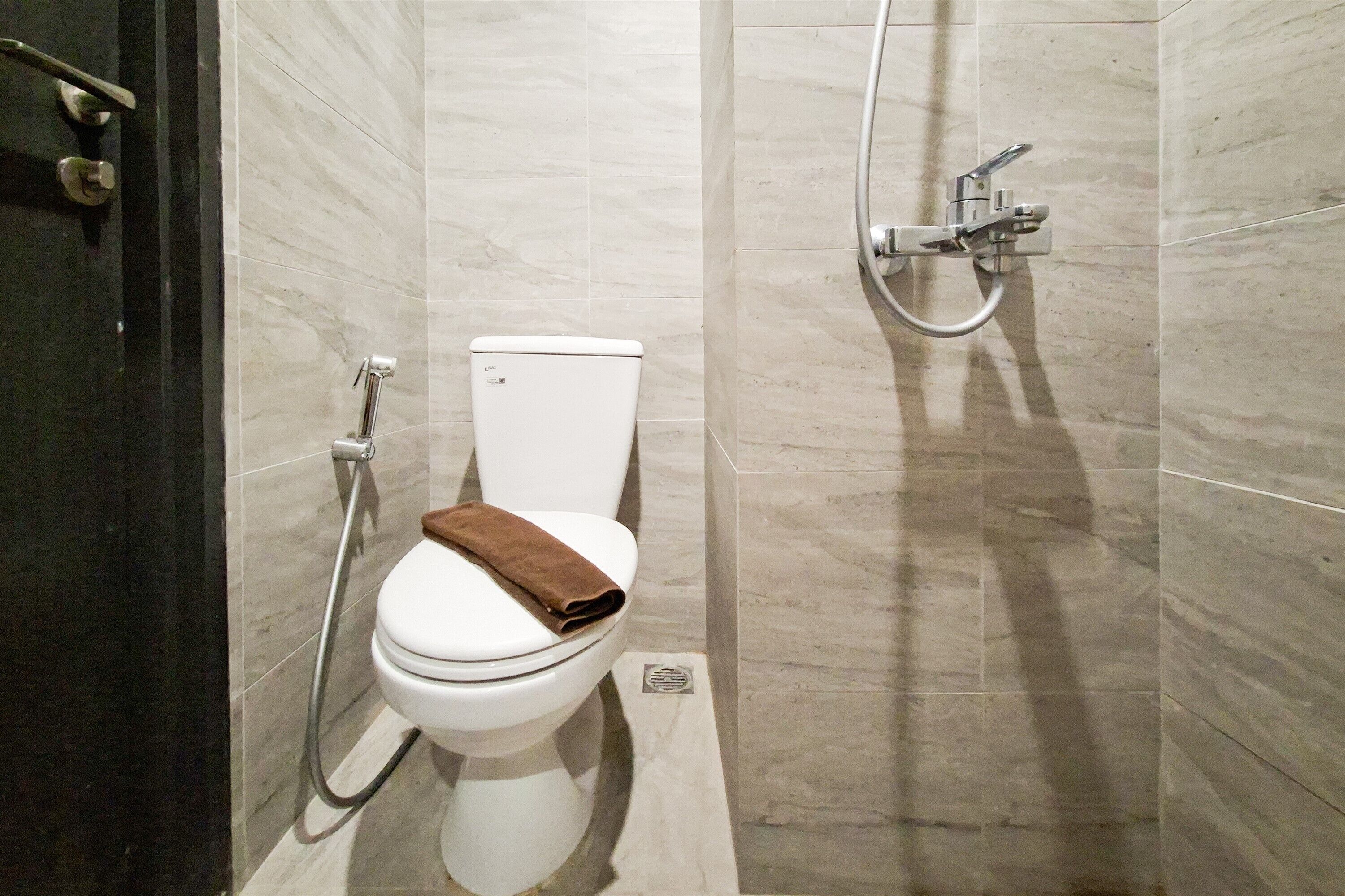 Baño con inodoro, ducha y pared con azulejos.