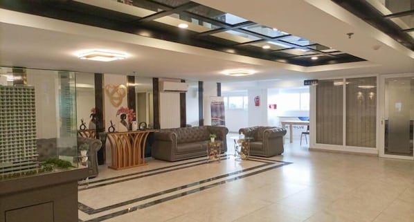 Un vestíbul modern amb taulell d'informació, zona de seients i una separació de vidre.