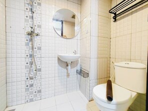 A bathroom with a toilet, sink, shower, and a mirror. - 2 Pax Neat Studio At De Prima Apartment (Medan)