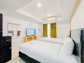 A hotel room with two beds, a TV, a clock, and a window with curtains. - 2 Pax Neat Studio At De Prima Apartment (Medan)