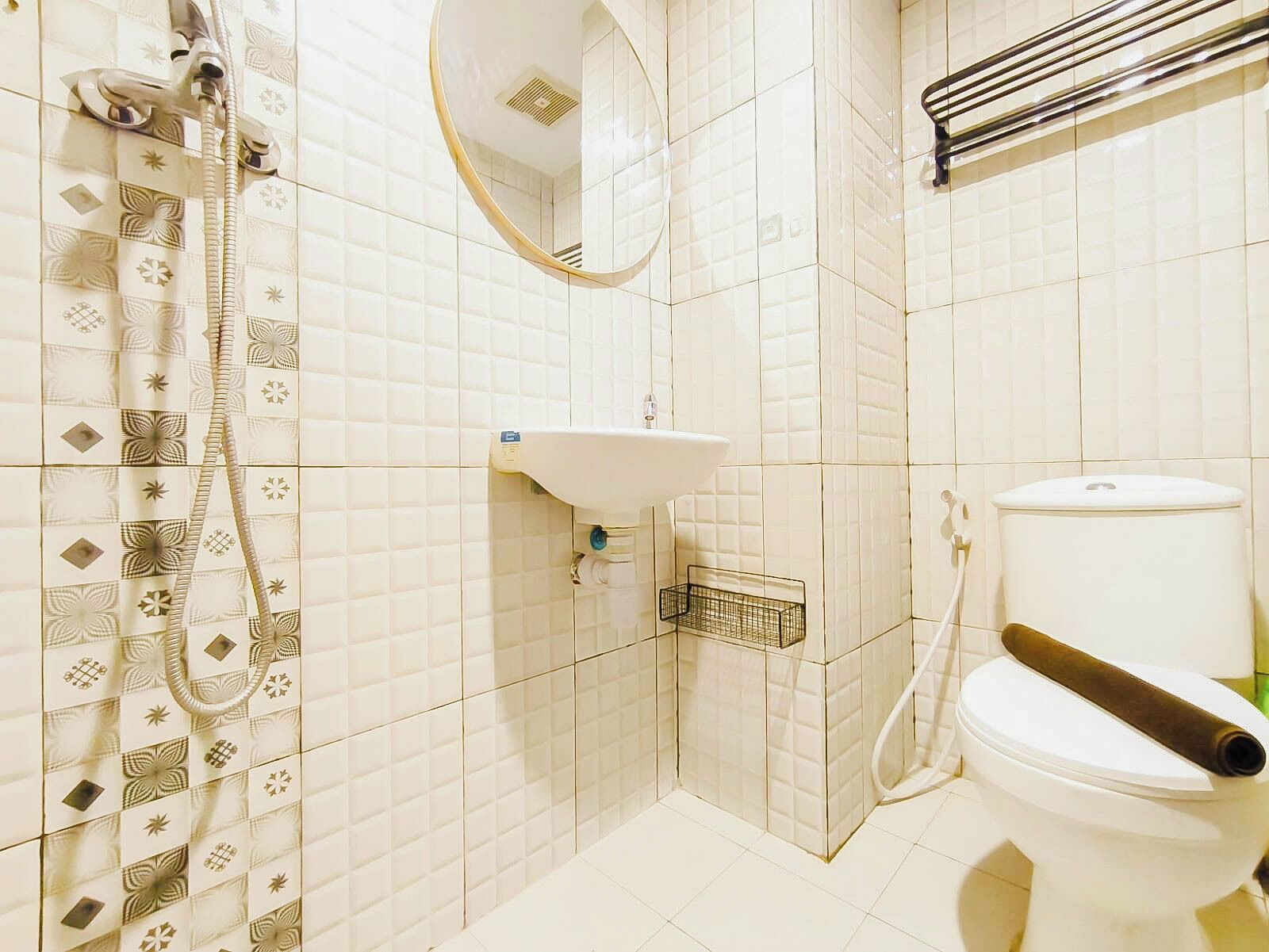A bathroom with a shower, toilet, sink, and a mirror.