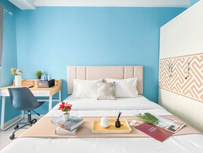 Ein Hotelzimmer mit Bett, Schreibtisch, Stuhl und einem kleinen Tisch mit Tablett.