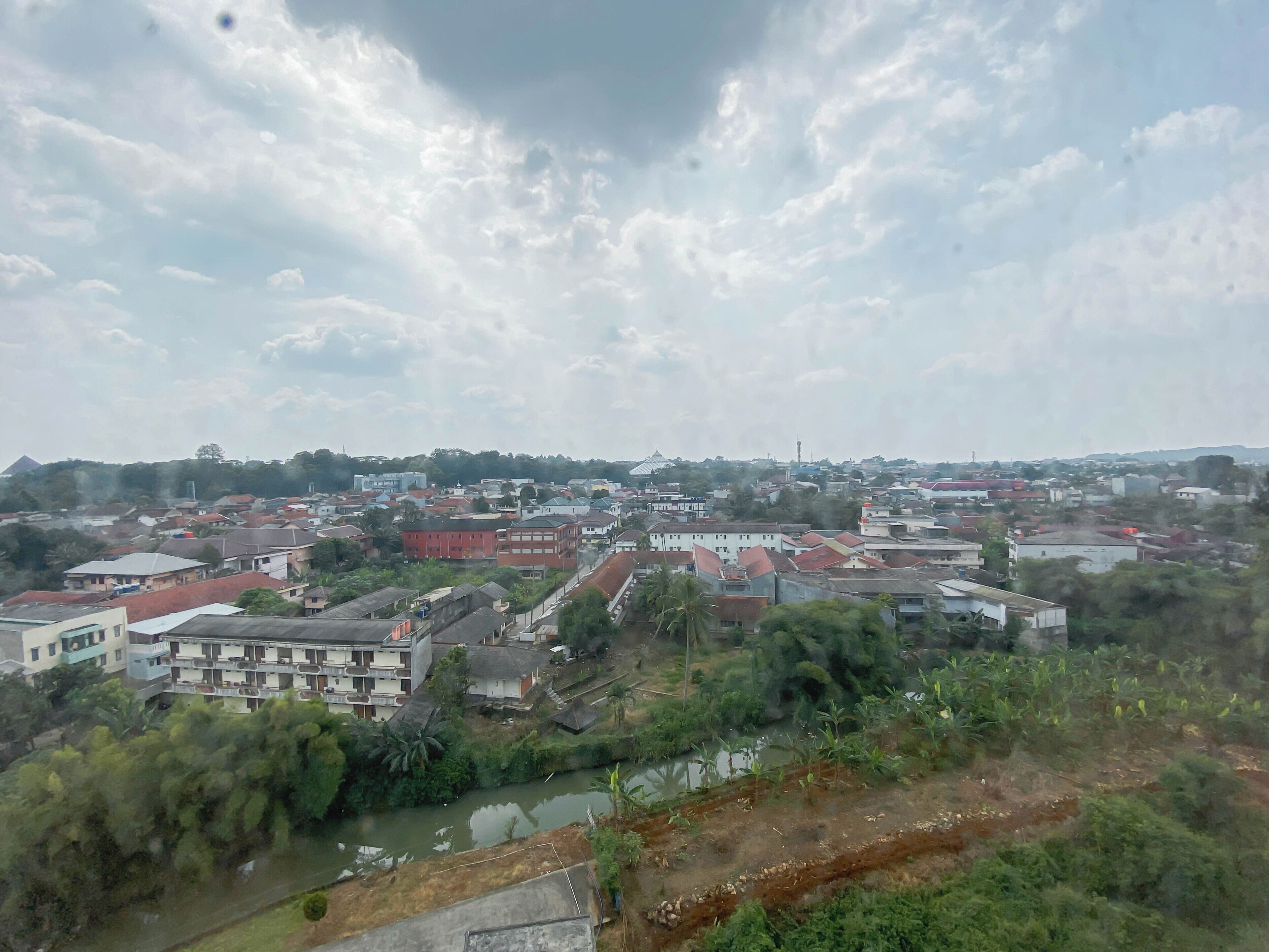 Un barrio residencial con casas, un río y una colina al fondo.