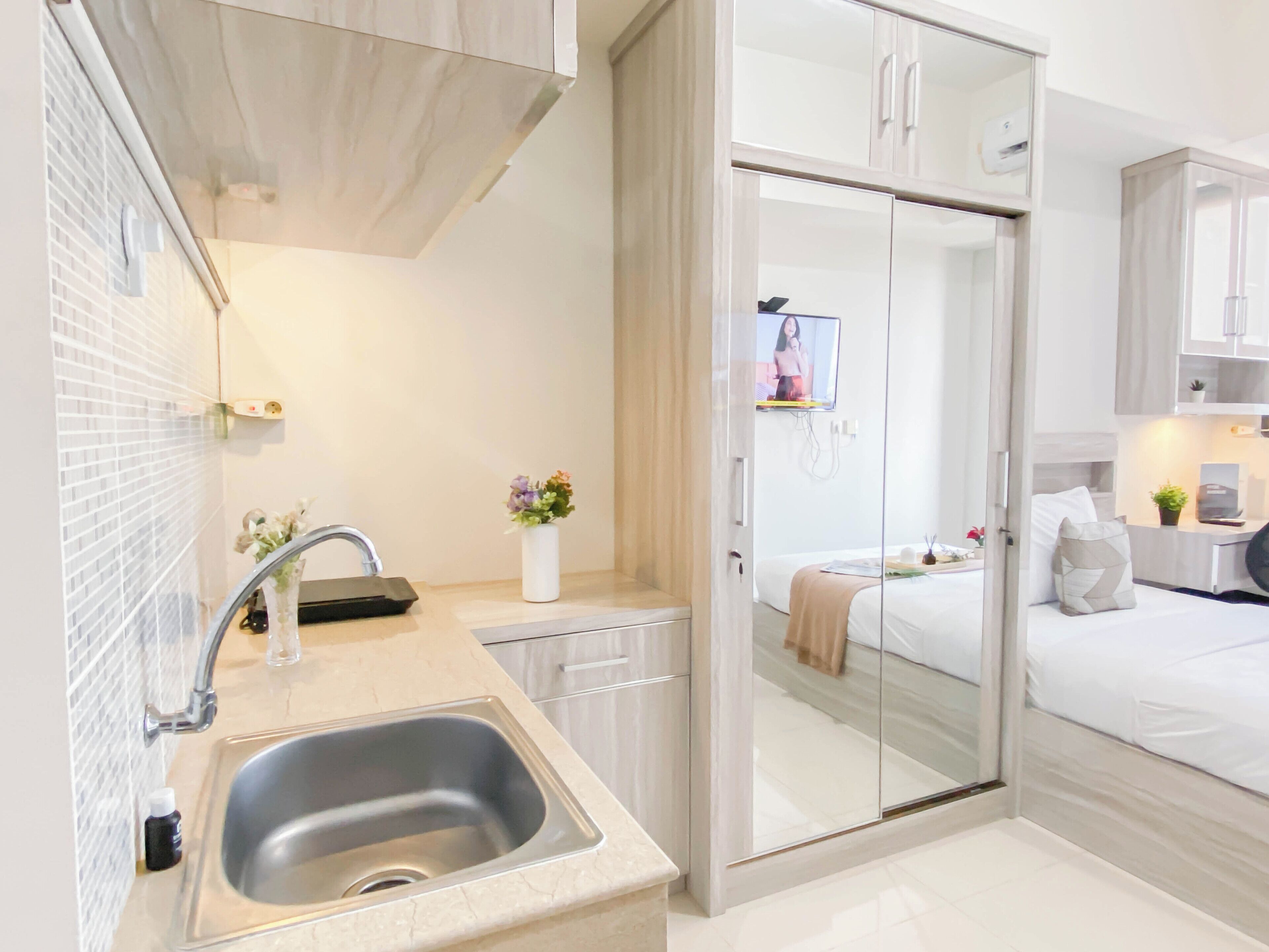 A modern kitchen with a sink, a small countertop, and a vase of flowers.