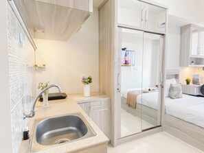 A modern kitchen with a sink, a small countertop, and a vase of flowers. - Good Location Studio Apartment At Evenciio Margonda (Depok)