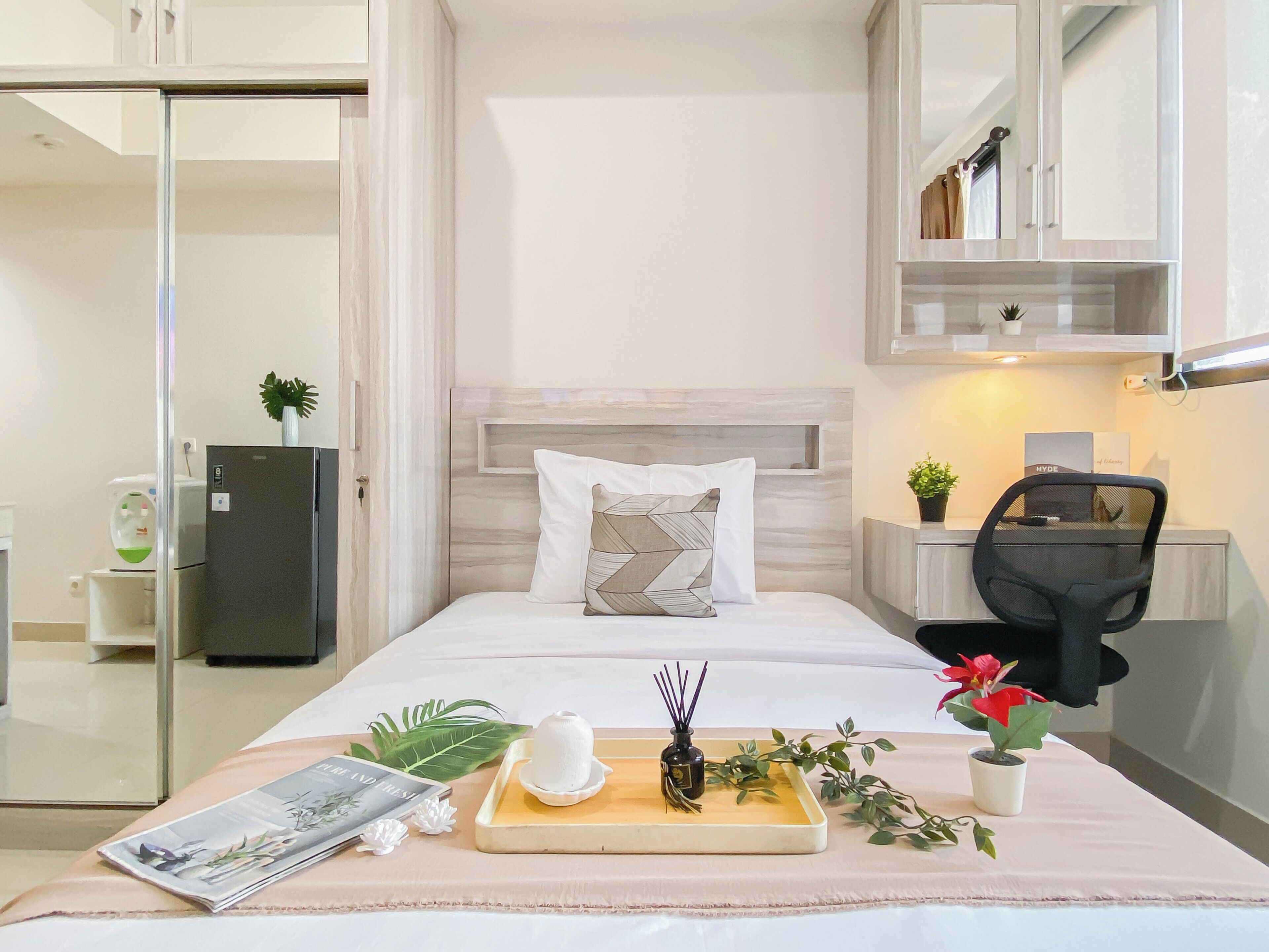 Une chambre bien rangée, avec un lit, une table de chevet, une chaise et un petit bureau équipé d’un ordinateur.