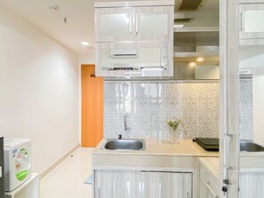A modern kitchen with white cabinets, a tiled backsplash, and a stainless steel sink. - Good Location Studio Apartment At Evenciio Margonda (Depok)
