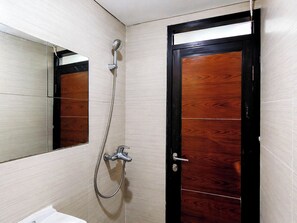 A bathroom with a wooden door, a shower with a handheld showerhead, and a mirror. - Compact 2 Pax Studio Room At Gateway Pasteur Apartment (Cimahi)