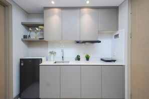 A modern kitchen with a built-in refrigerator, a sink, and cabinets. - 1Br Homey Areum Residence At Gold Coast (Jakarta)