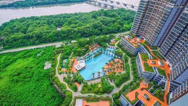 A high-rise building with a rooftop pool surrounded by greenery and a river in the background. - 1Br Homey Areum Residence At Gold Coast (Jakarta)