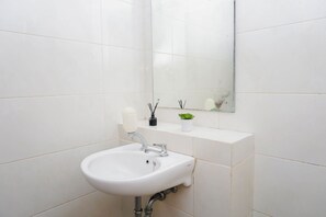 Ein Badezimmer mit weißem Waschbecken, Spiegel und gefliesten Wänden.