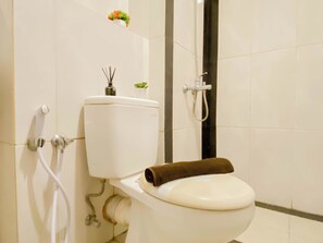 A bathroom with a toilet, a shower, and a wall-mounted sink. - Practical Studio For 2 Pax At Grand Kamala Lagoon Apartment (Bekasi)