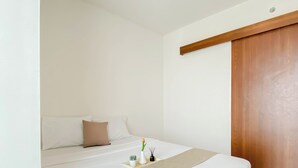 Una camera da letto con un letto, un armadio in legno e un piccolo cactus sul comodino.