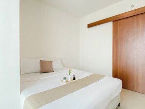 Un dormitorio con una cama, un armario de madera y una pequeña planta de cactus en la mesita de noche.