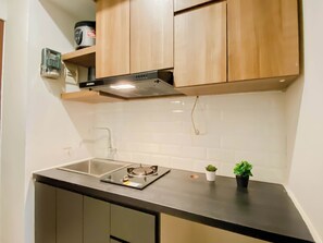 Una cocina con armarios de madera, un lavamanos de acero inoxidable, una estufa y una pequeña planta en maceta.