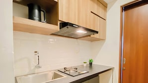 Una cucina con lavello, piano di lavoro, pensili, cappa aspirante e un piccolo sgabello.
