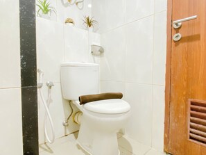 A bathroom with a toilet, a shower, and a wooden door. - Chic And Classic 1Br At Apartment Grand Kamala Lagoon (Bekasi)