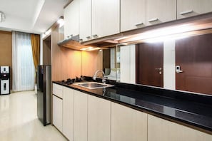 A modern kitchen with a stainless steel sink, a built-in stove, and light wood cabinetry. - 2 Pax Versatile Studio At Grand Sungkono Lagoon Apartment (Surabaya)