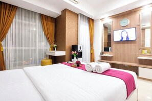 A hotel room with a large bed, a TV, a coffee machine, and a mirror. - 2 Pax Versatile Studio At Grand Sungkono Lagoon Apartment (Surabaya)
