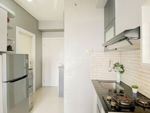A modern kitchen with a stainless steel refrigerator, a gas stove, and a white tiled backsplash. - Lovely Urban Living In 2Br At Apartment Green Pramuka City (Jakarta)
