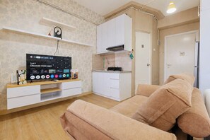 Ein Wohnzimmer mit Fernseher, Sofa und Küchenzeile.