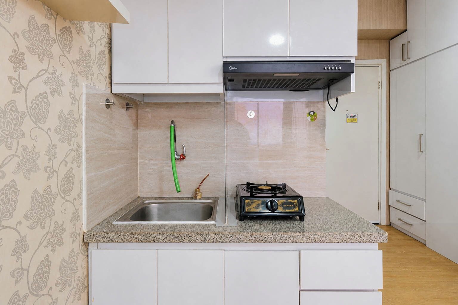 A compact kitchen with a gas stove, a sink, and a stainless steel countertop.