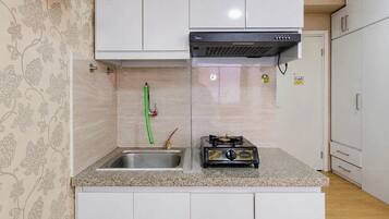 A compact kitchen with a gas stove, a sink, and a stainless steel countertop.