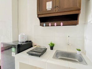 Una cucina con forno a microonde, piano cottura a induzione, lavello e pensile sopra il bancone.