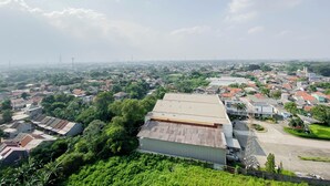 An aerial view of a residential area with houses, greenery, and a large industrial building. - Practical Studio At Gunung Putri Square Apartment (Gunung Putri)