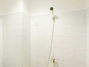 Una doccia con soffione a mano e rubinetteria a muro in un bagno rivestito di piastrelle.