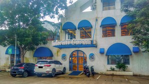 A building with a sign reading 'Intorini Garden,' a parking area with cars, and a blue awning over the entrance. - Practical Studio At Gunung Putri Square Apartment (Gunung Putri)