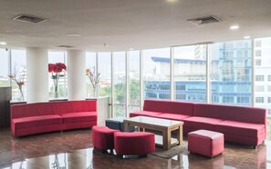 A modern lobby with large windows, red seating, and a polished floor. - Restful 1Br With City View At Apartment Harco Mangga Besar (Jakarta)