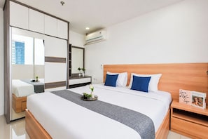 Ein Hotelzimmer mit Bett, Nachttisch, Schminktisch und Spiegel, sowie einer Klimaanlage.