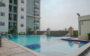 A swimming pool with a wooden deck, a lifeguard chair, and a no swimming sign. - Restful 1Br With City View At Apartment Harco Mangga Besar (Jakarta)