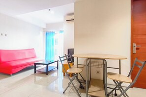 A living room with a red sofa, a small table, and two chairs. - Cozy Living 2Br Apartment At High Point Serviced (Surabaya)