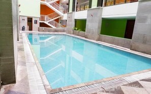An indoor swimming pool with a tiled deck, a staircase, and a green wall. - Cozy Living 2Br Apartment At High Point Serviced (Surabaya)
