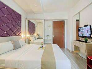 Een hotelkamer met een groot bed, een televisie, een bureau en een spiegel.