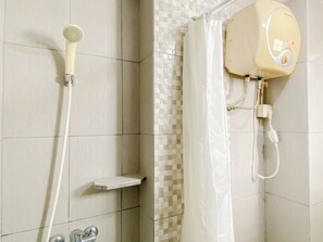A shower area with a handheld showerhead, a wall-mounted showerhead, and a shower curtain. - Comfortable And Decent 2Br At Apartment Kemang View (Bekasi)