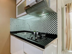Una cocina con salpicadero a cuadros blancos y negros, un lavamanos de acero inoxidable y una estufa a gas.